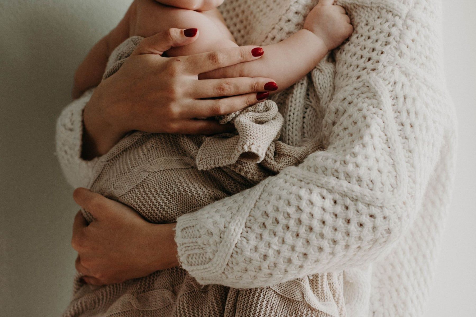 Ibu menggendong bayi dengan tenang menggunakan kain linen netral BabyNest
