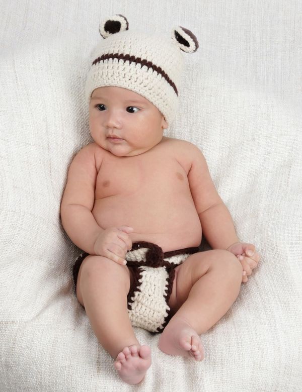 Bayi mengenakan Topi Bonnet Rajut Tangan Heirloom warna krem