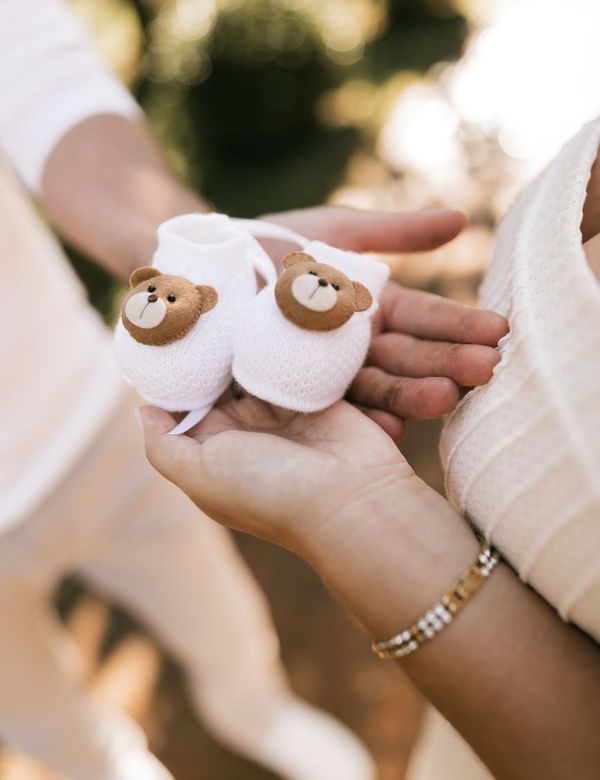Sepasang Booties Prewalker Katun Lembut dipegang lembut oleh tangan ibu